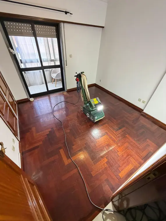 Máquina de afagar em trabalho sobre um pavimento em lamparquet